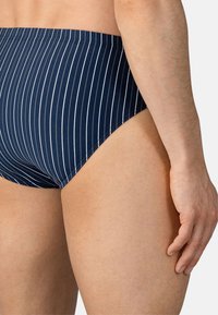 Navy och vita randiga badbyxor med hög midja, tillverkade av elastiskt tyg, med en mjuk yta och en kroppsnära passform.