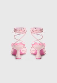 Roze hoge hakken met een strappy ontwerp en knopen rond de enkel, open teen en een chunky hak. Glad textuur en glanzende afwerking.