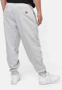Gray sweatpants made of soft fabric, featuring an elastic waistband, two side pockets, and a small logo patch on the back.