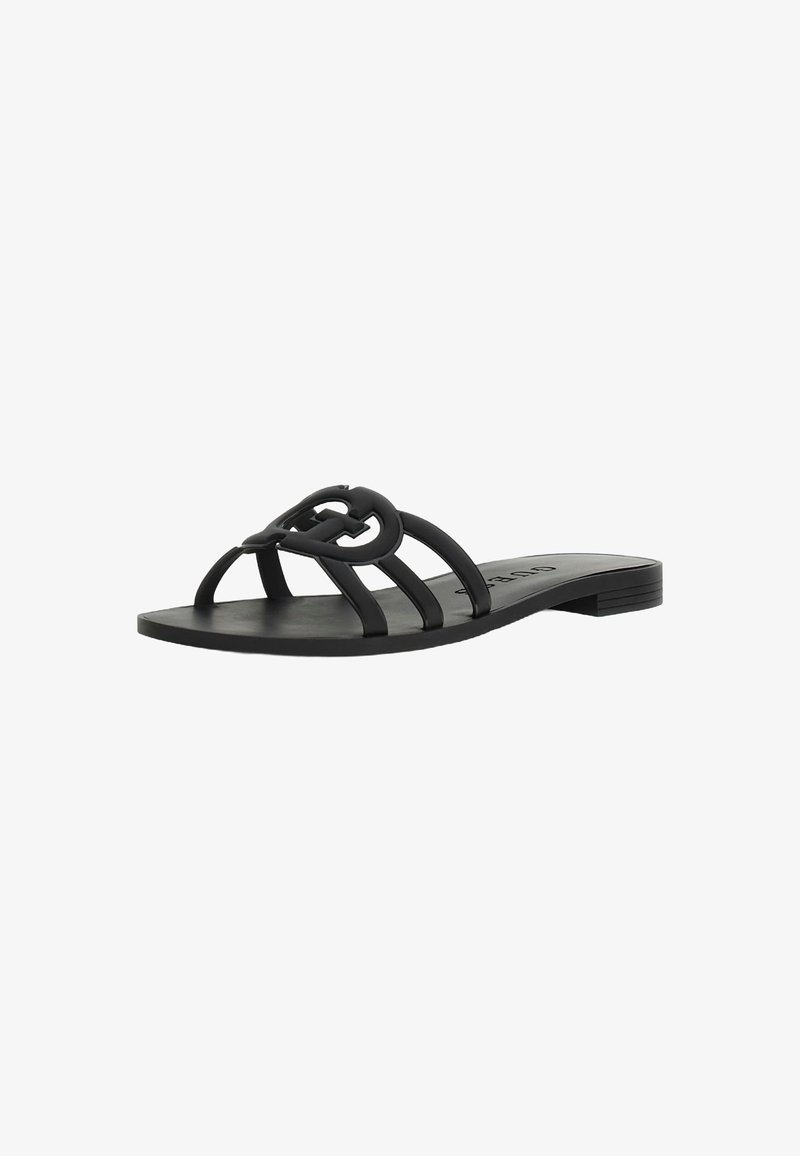 Sandalia plana negra con múltiples correas delgadas, que presenta un acento decorativo de cadena en la parte superior. Textura mate suave, diseño minimalista.