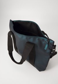 Schwarze und türkisfarbene wasserdichte Tasche mit doppelten Griffen, Reißverschluss und geräumigem Innenraum. Verfügt über eine kleine Innentasche und eine robuste Bauweise.