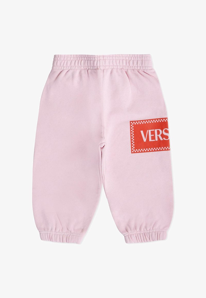 Pantalon de survêtement en coton rose avec taille élastique et poignets élastiques. Présente un patch rectangulaire rouge avec "VERS" en texte blanc, bordure à carreaux.