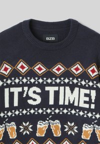 Pull bleu marine à col rond, affichant le texte blanc "C'EST L'HEURE !", des graphiques de chope de bière, et des motifs de diamants rouge, blanc et doré le long de l'empiècement.