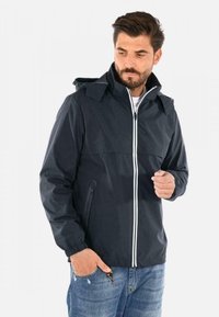 Giubbotto impermeabile navy con cappuccio, cerniera bianca a contrasto e polsini elasticizzati. Presenta una tasca laterale con zip e una texture liscia.