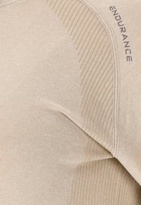 Beige Sportshirt mit glattem Stoff und geripptem Muster an den Schultern, dezentem "ENDURANCE"-Logo und flachgenähten Nähten.