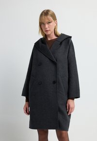 Abrigo de lana gris con capucha, diseño de doble botonadura, grandes botones negros y bolsillos laterales. Silueta de longitud media y estructurada.