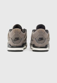 Nike-Schuhe in Grau und Schwarz, mit gepolstertem Schaft, strukturiertem Material, auffälligem Branding an der Ferse und kontrastierender weißer Sohle.