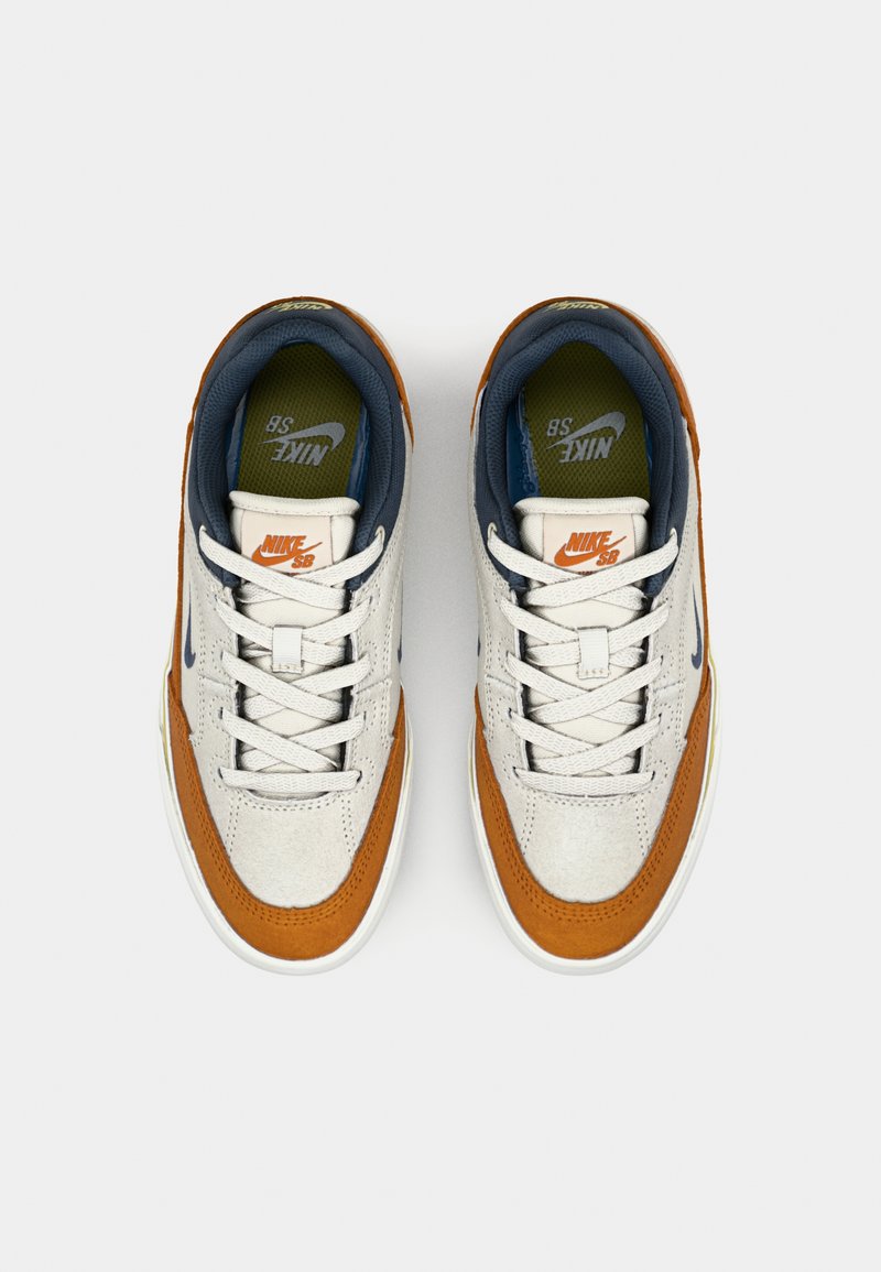 Nike SB Sneaker mit einer Kombination aus grauem Leder, orangefarbenen Wildlederakzenten, weißer Gummisohle und blauem Innenfutter.