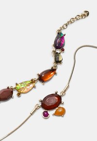 Collana multicolore con gemme luccicanti in varie forme, tra cui pera e ovale, montate su una struttura in tono oro con chiusura a catena.