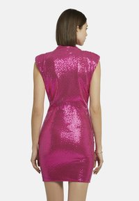 Robe courte en sequins roses avec une silhouette ajustée, des manches courtes et une fermeture éclair au dos. La texture réfléchissante accroît l'intérêt visuel.