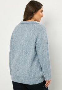 Helleblaue, gestrickte Sweater mit geripptem Saum und Bündchen. Verfügt über einen umschlagbaren Kragen und ein entspanntes Schnittdesign, das eine weiche Textur zur Schau stellt.