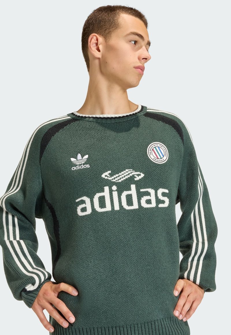 Maglione verde scuro lavorato a maglia con maniche lunghe, strisce bianche sulle spalle, grande logo "adidas" e distintivo circolare sul petto.