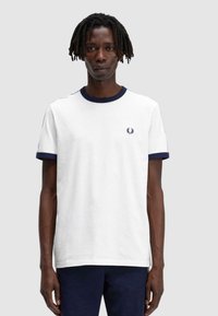 Camiseta blanca con cuello y puños de manga de canalé en azul marino. Presenta un pequeño logo bordado en el pecho. Material de algodón, cuello redondo.