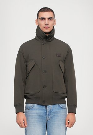 Dark green, padded jacket with high collar, front button closure, and two large pockets. Made from smooth, lightweight fabric.