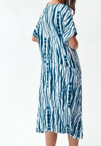 Vestido midi de tie-dye en azul y blanco que presenta mangas cortas, un corte relajado y un patrón de rayas abstractas en una tela ligera.