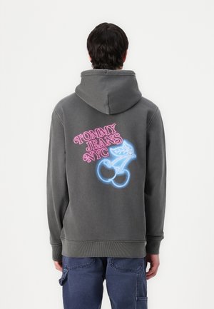 Grå hættetrøje med en kengurulomme, der har et pink og blåt grafisk design af kirsebær og teksten "TOMMY JEANS NYC" på ryggen.