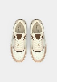 Βίγκαν αθλητικά παπούτσια με επάνω μέρος σε κρεμ απόχρωση, καφέ λεπτομέρειες, διάτρητο κουτί δαχτύλων και μπεζ σόλα. Διαθέτουν κορδόνια και μια μικρή ανθισμένη διακοσμητική λεπτομέρεια.