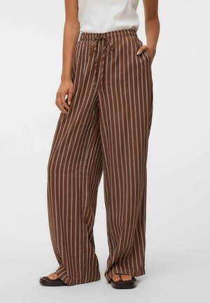 Pantalon large marron avec des rayures verticales blanches et une taille à cordon, porté avec des sandales foncées et un haut blanc sans manches.