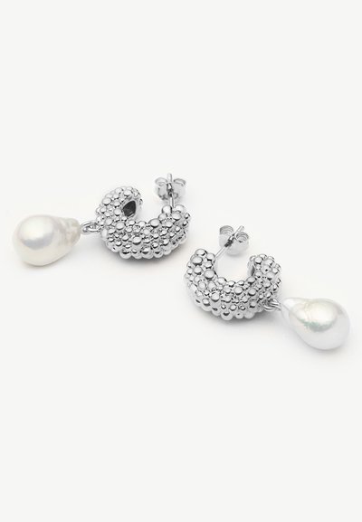 Σκουλαρίκια καρφάκια σε ασημί τόνο με υφή από συγκεντρωμένες χάντρες, το καθένα με ένα μεγάλο λευκό μαργαριτάρι σε σχήμα σταγόνας που κρέμεται κάτω από το καρφάκι.