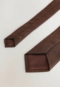 Brązowy krawat w wzór w jodełkę o gładkiej, teksturowanej powierzchni. Końce są zwężane, a od wewnętrznej strony mają tkane akcenty.