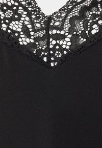 Tessuto nero con scollatura a V caratterizzato da un intricato bordo in pizzo nero. La texture è liscia con dettagli di design in pizzo.