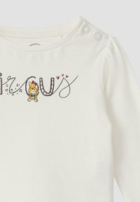 Witte lange mouw shirt met decoratieve tekst "CURIOUS," voorzien van een cartoonleeuw en harten. Twee drukknoopjes op de schouder.