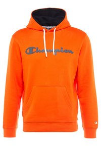 Sudadera naranja de tejido suave, con capucha forrada de negro, bolsillo frontal y un logo "Champion" gris en el pecho.
