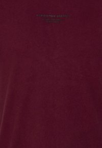 T-shirt in cotone bordeaux con collo rotondo e maniche corte, con testo blu sul petto che recita "Abercrombie and Fitch."