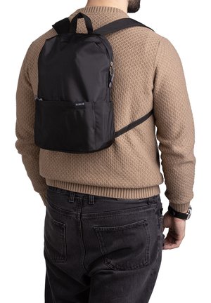 Black nylon backpack with padded back, adjustable straps, and front zip pocket. Features a smooth texture and minimalist design.