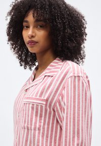 Κόκκινο και λευκό ριγέ πουκάμισο με κουμπιά και τσέπη, μαλακό ύφασμα, γιακάς και άνετη εφαρμογή.