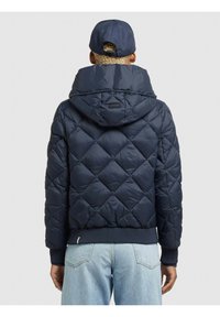 Chaqueta de plumas acolchada en color marino con capucha, puños y bajo acanalados, que presenta un pequeño parche de logo en la parte posterior y una textura suave y brillante.