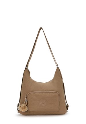 Sac à épaule marron avec poche zippée à l'avant, écusson rond avec logo et un petit porte-clés en peluche attaché à la tirette du zip.