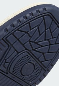 Navy rubber sole with textured surface, featuring geometric tread pattern and circular accent. Off-white edge around the sole.