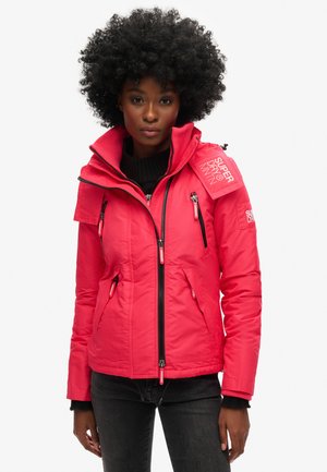 Chaqueta aislante roja con cuello alto, bolsillos con cremallera y acentos de logotipo. Presenta un diseño ajustado y una tela texturada para mayor calidez.