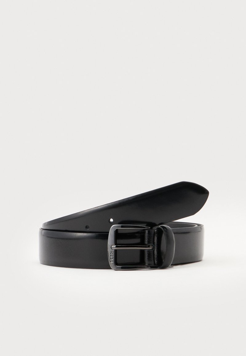 Ceinture en cuir noir roulée avec une boucle à ardillon métallique noire, sur un fond clair uni.