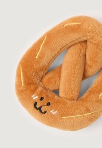 Soft, orange plush toy shaped like a pretzel with stitched smiling face and yellow embroidery lines, on a light background.