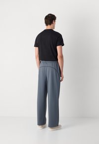 Camiseta negra y pantalones de chándal grises de pierna ancha, con una cinturilla elástica y detalles de costura sutiles, confeccionados con una tela ligera y suave.