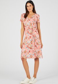Vestido envolvente floral en rosa con mangas cortas, que cuenta con un lazo en la cintura y un dobladillo que cae por encima de la rodilla; decorado con flores coloridas.