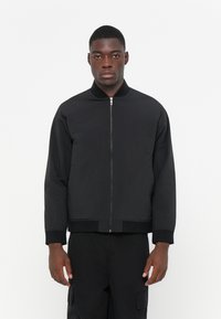 Black bomber jacket with a smooth finish, zip-up front, ribbed collar, and cuffs, featuring a relaxed fit and no visible patterns.