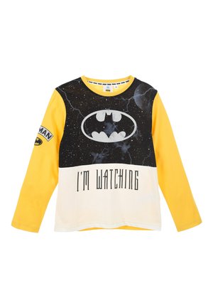 Yellow long-sleeve t-shirt featuring a black Batman logo over a starry background, with the text "I'M WATCHING" in bold black letters.