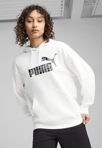 Felpa bianca con cappuccio realizzata in tessuto morbido, caratterizzata da un grande logo nero "PUMA" e da una grafica di un puma in salto sul petto. Tasche a canguro frontali.