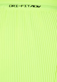 Lime vihreä, poimutettu kangas, jossa on sileä tekstuuri. Ominaisuudet ovat verkkomallinen vyötärö, johon on painettu mustalla "DRI-FIT ADV" ylhäältä.