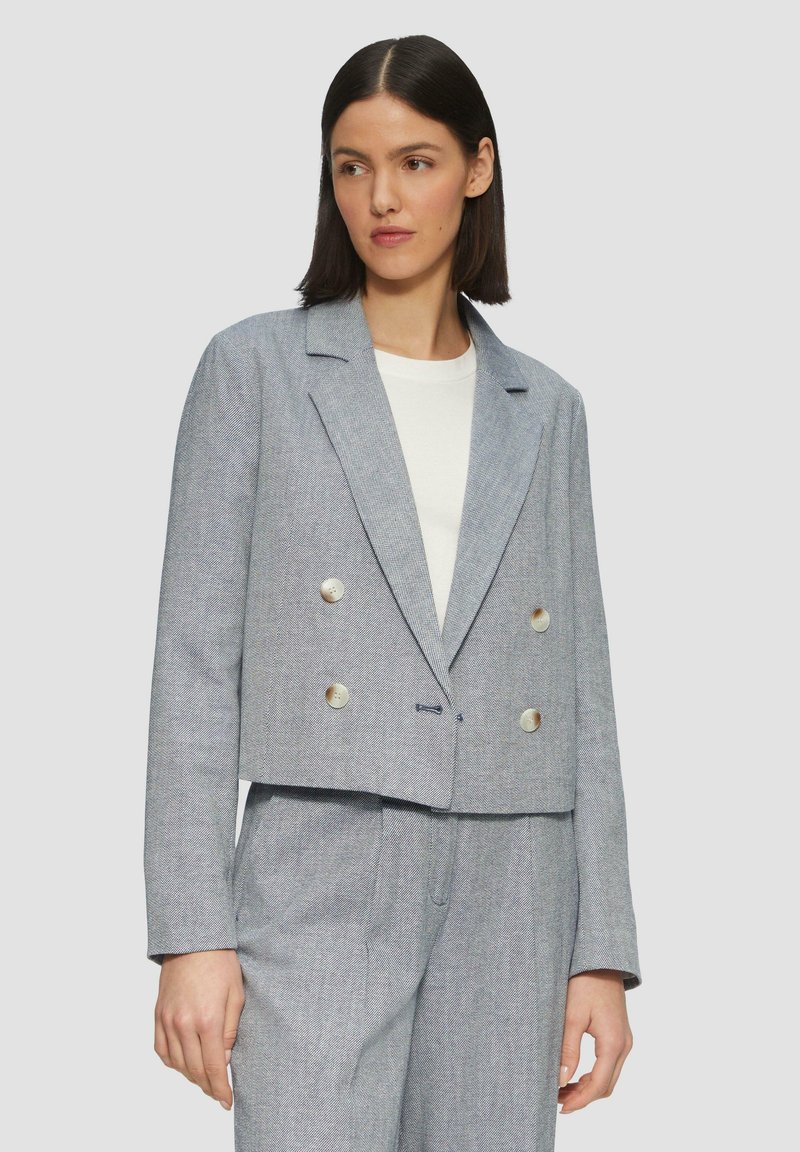 Dubbelzijdige blazer van lichtblauwe stof met een geweven patroon. Heeft een notch-kraag, twee grote knopen en een cropped ontwerp.
