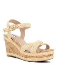 Sandale à talon compensé beige avec une plateforme en liège, des sangles en textile tressé, une boucle réglable à la cheville et une doublure intérieure lisse.