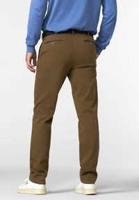 Person wearing brown pants, a blue long-sleeve shirt, white sneakers, and a black belt, shown from the back on a plain background.
