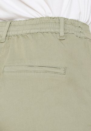 Lichtolijfgroene broek met een gerimpelde tailleband, platte achterzak en een gladde textuur. Gestikte details rond de tailleband.