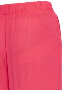 Pantalon à taille élastique couleur corail avec tissu texturé et détail de poche latérale.