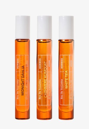 Tres frascos de perfume de vidrio ámbar con tapones blancos etiquetados como Midnight Dahlia, Cashmere Kumquat y White Tea de Korres.