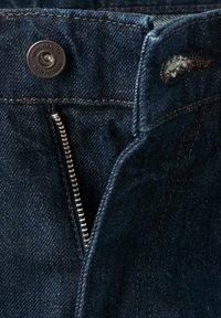 Dark blue denim fabric featuring a zip fly with silver hardware, brown button closure, and subtle stitching details. Worn look at the waistband.