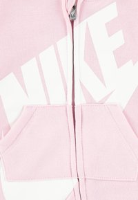 Ροζ hoodie με φερμουάρ, μεγάλο λευκό λογότυπο "NIKE", τσέπες καγκουρό, ριμπ μανσέτες και λεία υφή από μείγμα βαμβακιού.